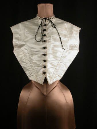 Chemisette, front, circa 1850, white moire, waistcoat shaped and boned laced at back. Black silk buttons, neck trimmed with lace threaded with black velvet ribbon, National Trust Collections.:
