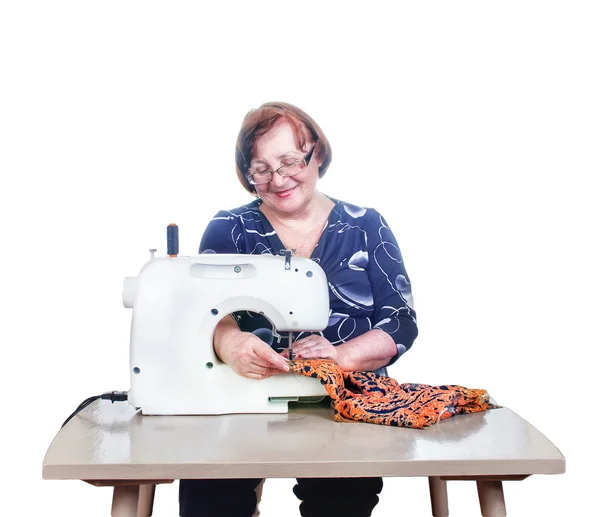 Пожилая женщина шьет с ее швейной машины. Изолированные на белом фоне — стоковое фото