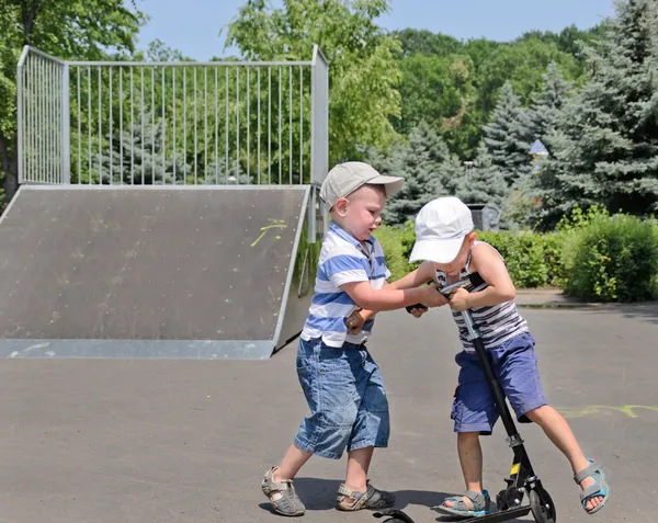 Две молодые мальчики борются за скутер — стоковое фото