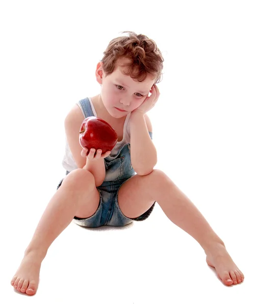 Грустный мальчик с яблоком в руке — стоковое фото