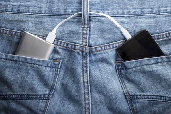 Банк питания находится в заднем кармане джинсов зарядки мобильного телефона — стоковое фото