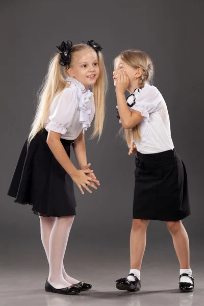 Две маленькие школьницы, выступая и делиться секретами — стоковое фото
