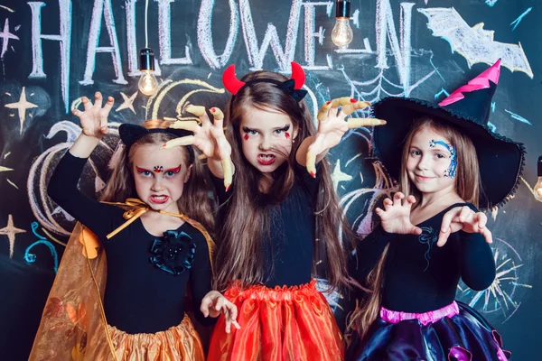 Девушек, одетых в костюмы Хэллоуина, показывают эмоции ведьм. Хэллоуин с группой детей — стоковое фото