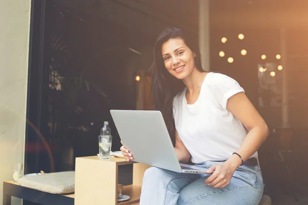 Smiling hipster girl is using laptop computer to connect to internet for chatting — стоковое фото