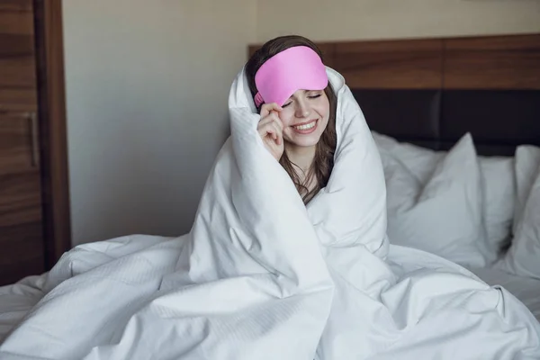 Молодая девушка с маской для спать в постели — стоковое фото