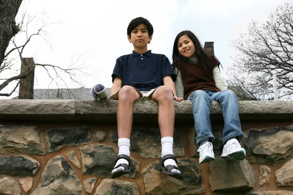 Двое детей, сидя на выступе скалы — стоковое фото
