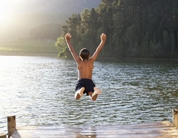 Маленький мальчик, вскакивающий в озеро — стоковое фото